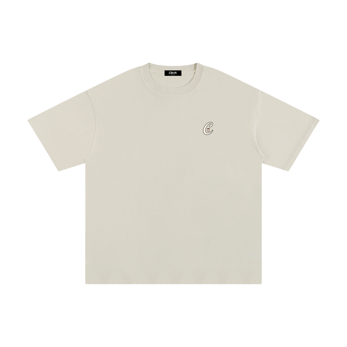 A light beige crewneck t-shirt with a small black circular logo on the left chest, displayed flat against a solid white background.