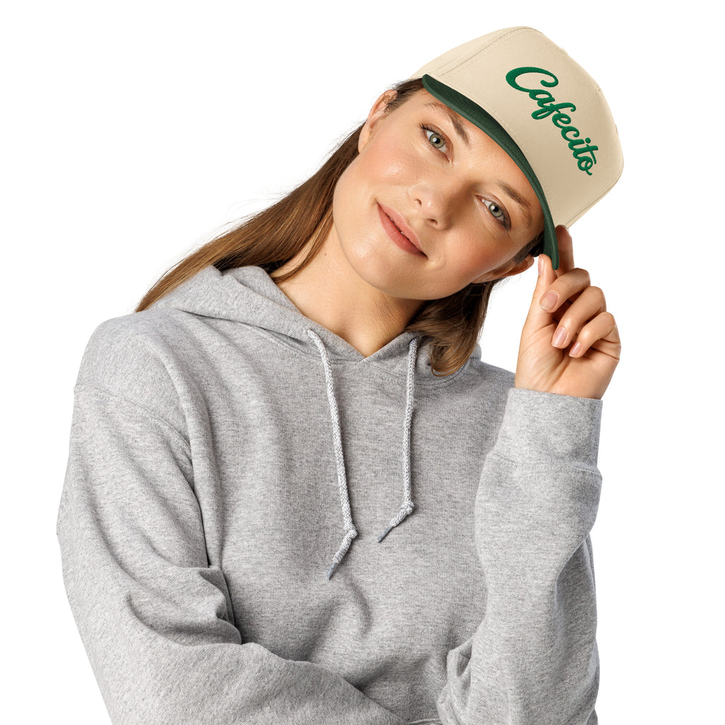 Person wearing a gray hoodie and beige cap with cafecito logo on a white background